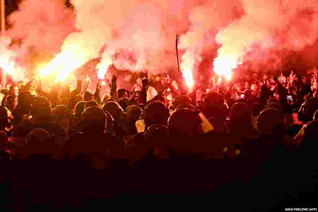 Protesters light flares and gesture next to riot police during a rally against a controversial law on presidential powers in Podgorica on December 12.