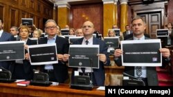 Pojedini opozicioni poslanici u Skupštini Srbije drže natpis "Mrak u Srbiji bez slobodnih medija" u znak podrške televizijama N1 i Nova S koje su 6. decembra prekinule emitovanje. 