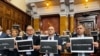 Pojedini opozicioni poslanici u Skupštini Srbije drže natpis "Mrak u Srbiji bez slobodnih medija" u znak podrške televizijama N1 i Nova S koje su 6. decembra prekinule emitovanje.