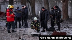 Emergency services and police officers examine parts of a drone at the site of a building destroyed by a Russian drone attack in Kyiv on December 14.