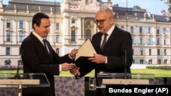 Kosovar Prime Minister Albin Kurti (left) hands over the country's official application for EU candidancy status to Czech Minister of EU Affairs Mikulas Bek in Prague on December 15.