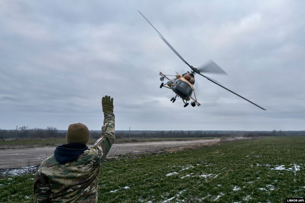 Një ushtar ukrainas duke bërë me dorë drejt një helikopteri luftarak që po kthehej nga një mision.