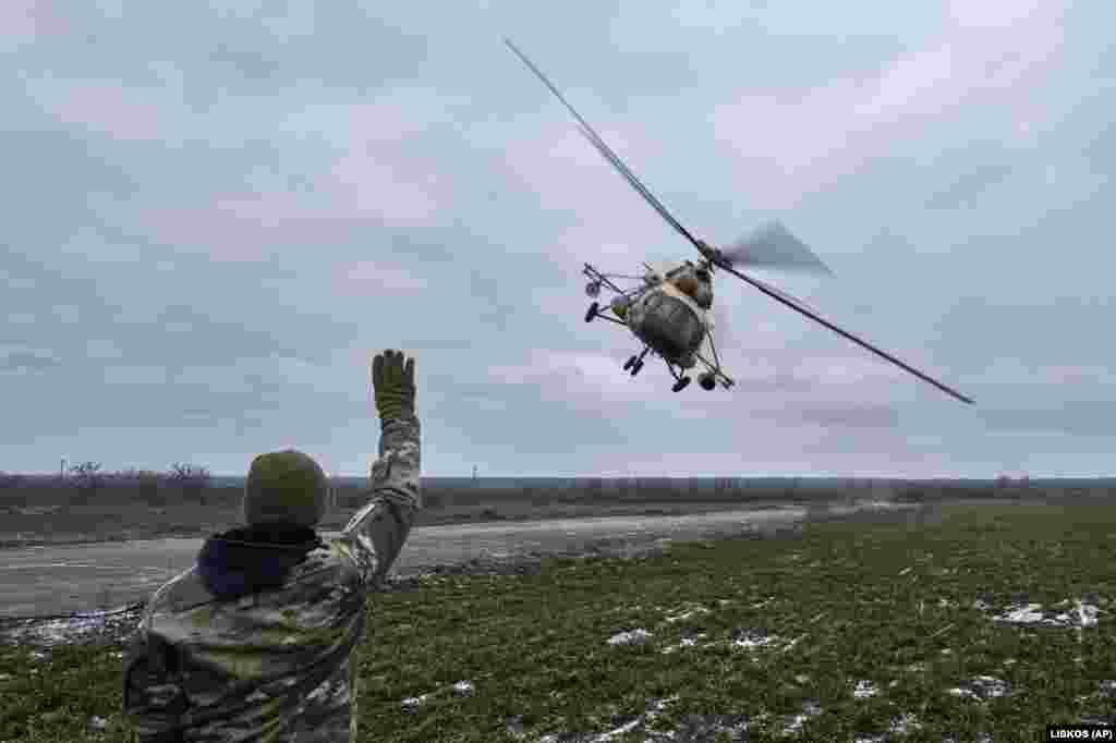 A Ukrainian soldier waves to a combat helicopter as it returns from a mission.