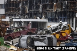 Разрушенные автомобили свалены рядом с торговым центром, разрушенным во время боев в Мариуполе, Украина, 10 декабря 2022 года