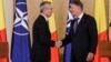 NATO Secretary-General Jens Stoltenberg (left) shakes hands with Romanian President Klaus Iohannis in Bucharest. (file photo)