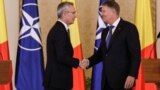 NATO Secretary-General Jens Stoltenberg (left) shakes hands with Romanian President Klaus Iohannis in Bucharest. (file photo)