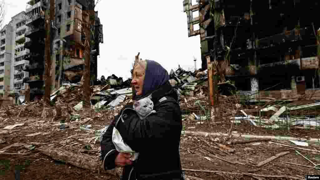 Жена държи котката си пред жилищни сгради, разрушени от руските войски при нахлуването им в Бородянка край Киев. 5 април 2022 г.