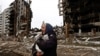 A woman carries her cat as she walks past buildings that were destroyed by Russian shelling in Borodyanka in Ukraine's Kyiv region in April. 