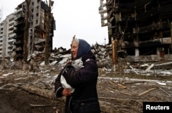 Женщина несет свою кошку, проходя мимо зданий, разрушенных российскими обстрелами, на фоне вторжения России в Украину в Бородянке, Киевская область, Украина, 5 апреля 2022 года