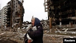 A woman carries her cat as she walks past buildings that were destroyed by Russian shelling in Borodyanka in Ukraine's Kyiv region in April. 