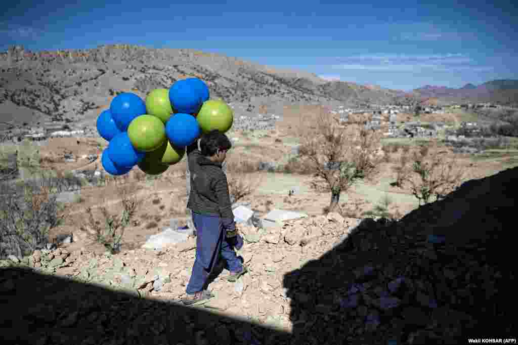 Një djalë afgan duke mbajtur disa balona teksa ecën përgjatë një shtegu në distriktin Barmal të provincës Paktika, më 15 dhjetor.