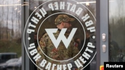 A man wearing a camouflage uniform walks out of the Wagner Center in St. Petersburg, Russia.