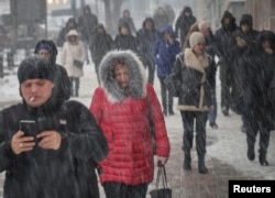 People walk down a street amid a snowfall in central Kyiv on December 7.