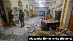 Ruski vojni istražitelji stoje pored tijela osobe ubijene u granatiranju omladinskog centra u Donjecku 6. decembra 2022.