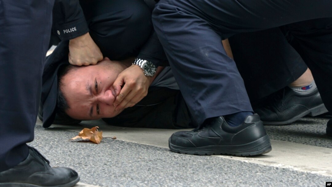 Mai mulți polițiști imobilizează un protestatar în Shanghai, China, pe 27 noiembrie 2022. În ultimele zile au avut loc proteste în cel puțin zece mari orașe față de strategia severă „Zero Covid” a regimului de la Beijing.