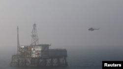 Вертолет приземляется на нефтяной платформе в Каспийском море. 