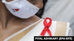 یک داوطلب روبانی به علامت بیماری ایدز در روز جهانی ایدز به لباس خود سنجاق کرده است