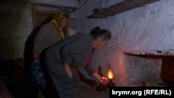 Марина Серединова та Наталя Трентинець у підвалі запалюють гасову лампу під час російського обстрілу