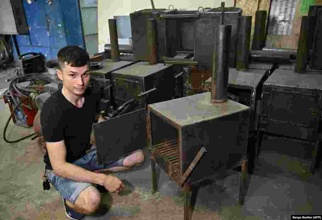 Кузнец Антон Зайка демонстрирует новую печь в своей мастерской в ​​Сумах. Дровяные печи 32-летний мужчина разработал специально для использования в окопах в качестве источника тепла и для приготовления пищи.