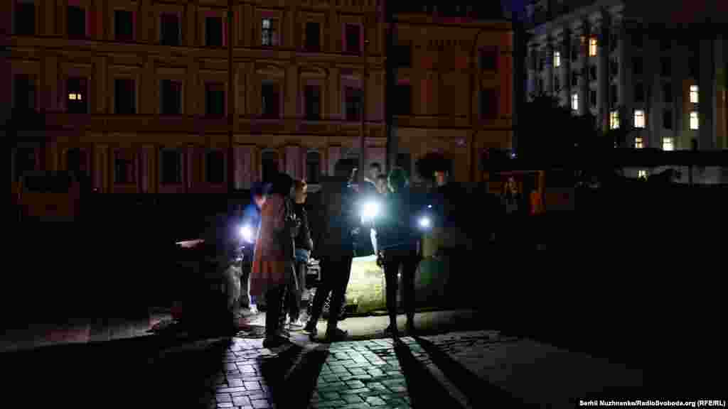 Oamenii folosesc lanternele telefoanelor mobile, în timpul unor deconectări a energiei electrice, Kiev, 19 octombrie 2022.
