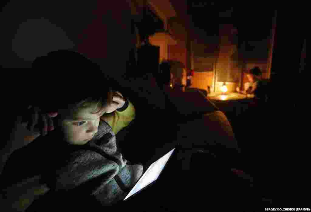 A boy plays with a tablet during a planned power outage in Kyiv on October 20. The government ordered Ukrainians to minimize electricity use from 7 a.m. to 11 p.m. and warned that temporary blackouts were possible. &nbsp;