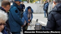 Žena drži psa dok civili evakuisani iz grada Hersona pod ruskom kontrolom čekaju da se ukrcaju u autobus koji ide ka Krimu, u grad Oleški, 22. oktobar.