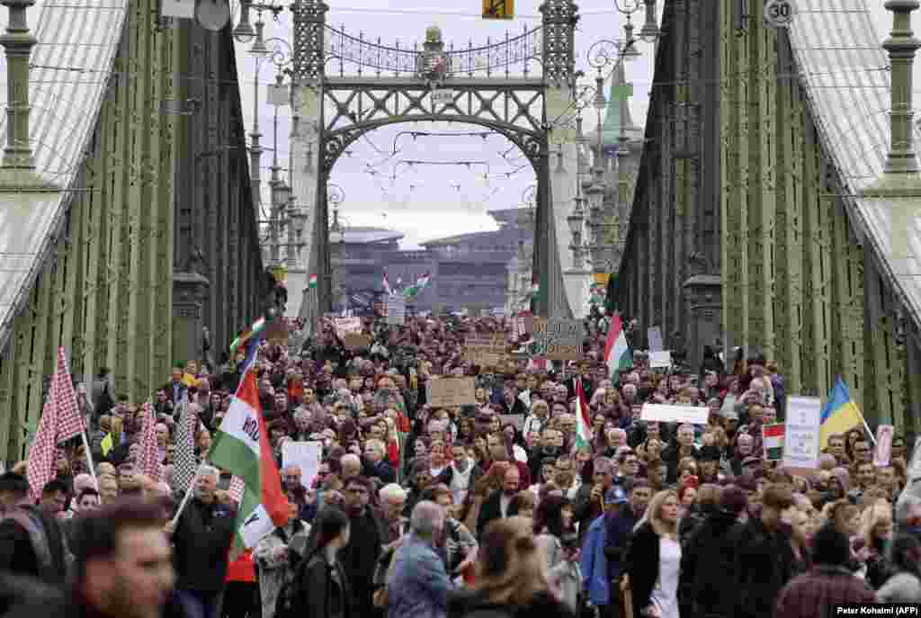 Протестиращи преминават през Моста на свободата в Будапеща на 23 октомври. Хиляди хора се събраха на един от най-големите протести, с които се е сблъсквало правителството на Виктор Орбан. Унгарците протестираха по различни въпроси, сред които условията на труд на учителите и тежката икономическа ситуация в Унгария.