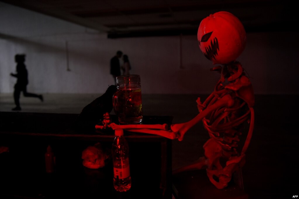 Një burrë shihet duke vrapuar pranë një skeleti në një festë Halloweeni në Prishtinë, 31 tetor 2022.