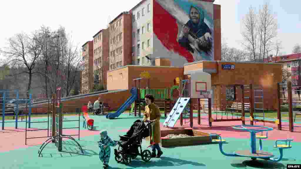 Стенопис над детска площадка в московското предградие Рютов, изобразяващ възрастна жена с червено знаме. Картината, заснета през април, препраща към известна случка малко след руската инвазия, при който пенсионерка излиза от къщата си близо до украинския град Харков със знаме на Съветския съюз, за да поздрави войници, за които предполага, че са руски. Мъжете всъщност са украински военнослужещи.
