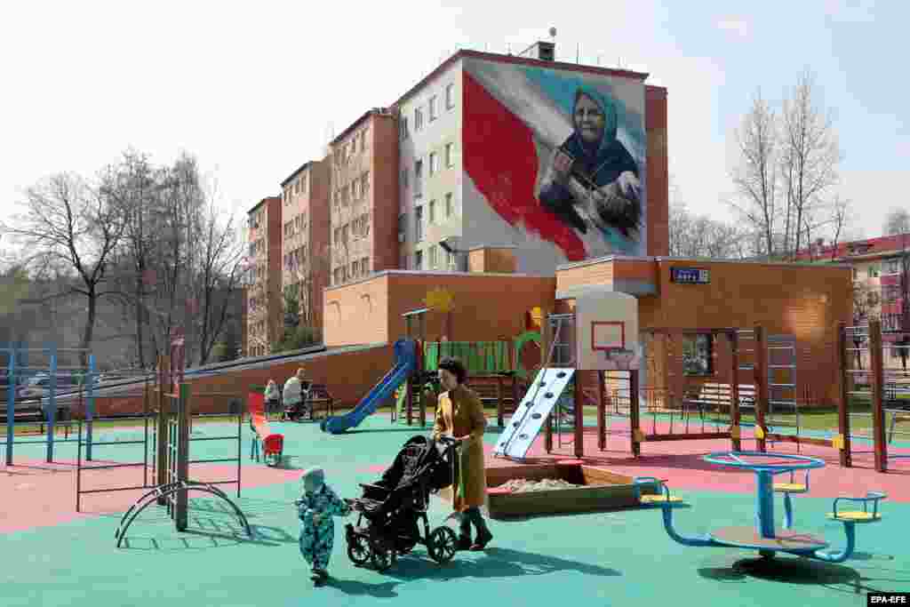 A mural above a playground in Reutov, near Moscow, depicting an elderly woman with a red flag. The large-scale painting, which was photographed in April, references a notorious incident shortly after the Russian invasion in which a pensioner emerged from her house near Kharkiv holding a flag of the Soviet Union to greet soldiers she assumed were Russian. The men were in fact Ukrainian servicemen.