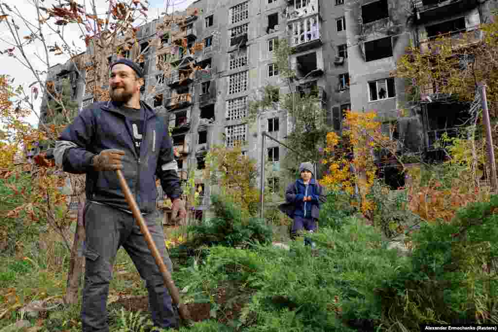 A Mariupol man and his young nephew work in the yard of a damaged building on October 29.&nbsp; Mariupol was captured by Russian forces in May after months of fighting left some 90 percent of the city&#39;s buildings damaged or destroyed. Thousands of people died in what became known as the siege of Mariupol.