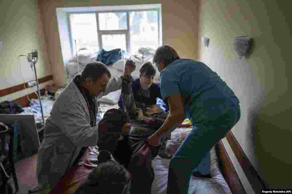 Doctor Yuriy Kuznetsov (left), a trauma surgeon, helps nurses move a patient onto a bed. The handful of doctors, nurses, paramedics, and pathologists who stayed during the Russian occupation were the only hope for residents of Izyum as the city&nbsp;rapidly filled with the sick and wounded. &nbsp;