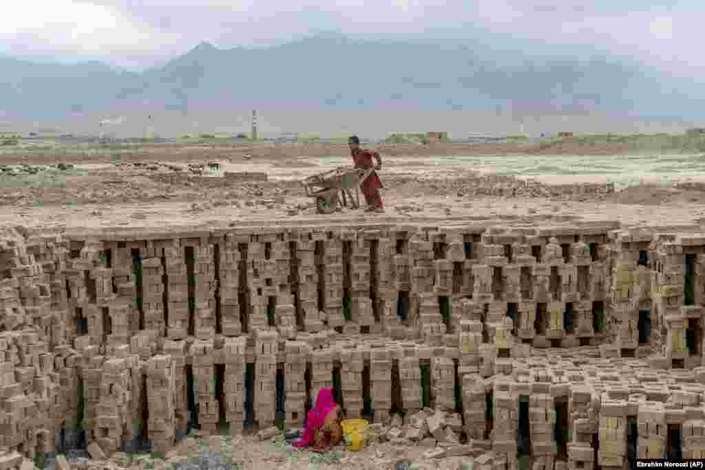 Some children load and push wheelbarrows full of dried bricks to the kiln for firing, then push wheelbarrows full of fired bricks back to the loading area.&nbsp; &nbsp;