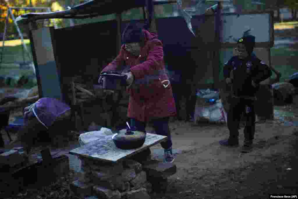 Irina Pancsenko vesz le egy fazék ételt a rögtönzött tűzhelyről 9 éves unokája, Artem társaságában Kivsarivkában. &quot;Hideg van és bombáznak&quot; - mondta Artem, miközben nagymamájának segített a főzésben. A Donyecktől északra fekvő Kivsarivka lakói közel három hete gáz, víz és áram nélkül élnek, miután az orosz rakétacsapások tönkretették a város közműveit. &nbsp;