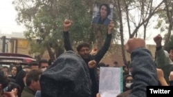 Protester Mehrshad Shahidinejad (center) holds up a picture of his father, who is one of the victims of the crackdown on protests in Iran, on November 3.