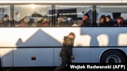 A Polish soldier passes by as people sit in a bus after they crossed the Polish-Ukrainian border on March 18, 2022. More than 3 million Ukrainians fled across the border, mostly women and children, after Russia's invasion, according to the UN.