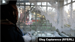 Жена гледа счувен прозорец в къща в село Наславча