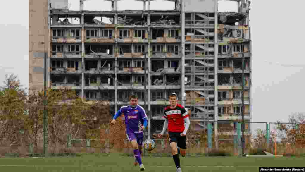 Futballisták edzenek egy súlyosan megrongálódott épület szomszédságában