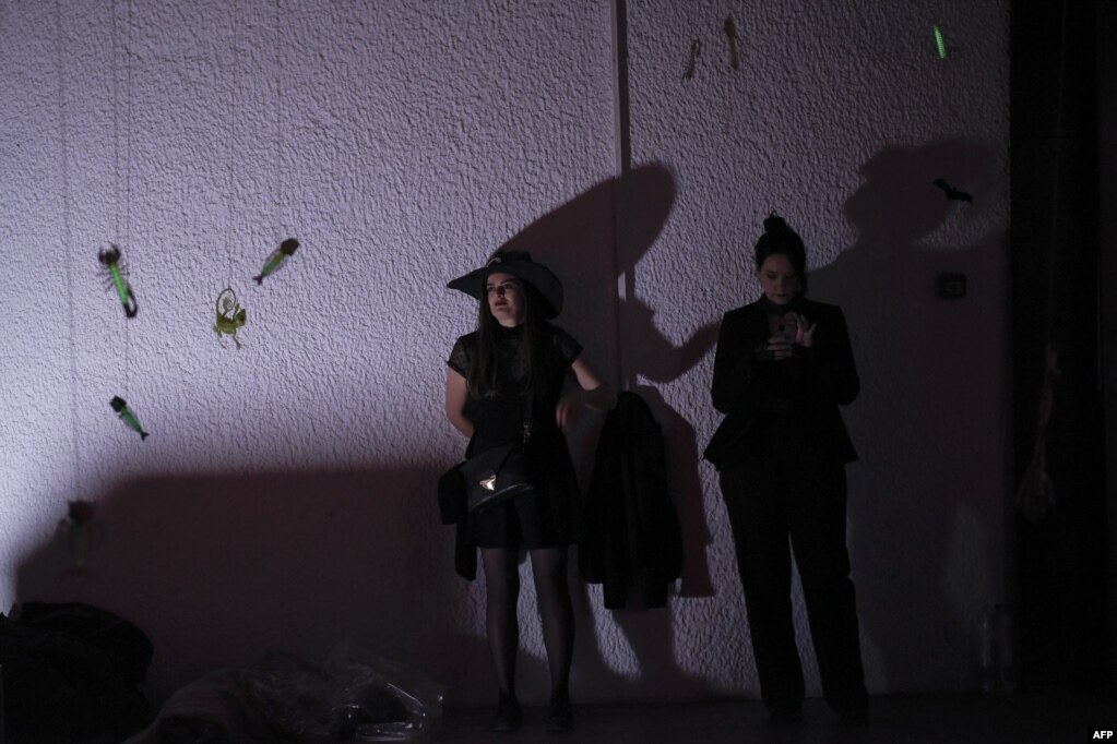 Dy vajza duke qëndruar pranë një muri të zbukuruar gjatë një feste në Natën e Shtrigave.