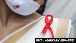 INDIA HEALTH WORLD AIDS DAY -- A voulnteer wears a red AIDS ribbon badge during an awareness rally on World AIDS Day, organized by the Durbar Mahila Samanwaya Committee in the Sonagachi red light district, in Kolkata, India 01 December 2020