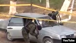 Police examine a car at the site of an attack in Taraz on November 12.