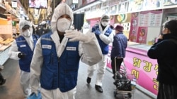 Работники в защитных костюмах проводят дезинфекционные работы на рынке в Сеуле. 24 февраля 2020 года.