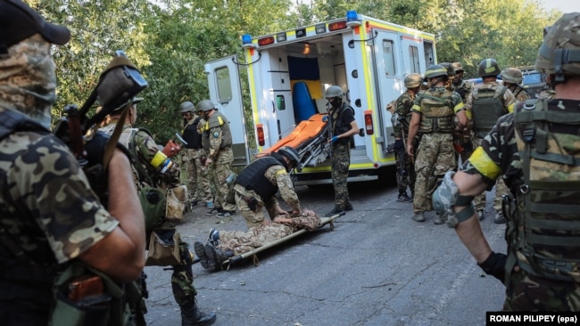 Украинские бойцы спасают товарища, раненного во время боя с российскими гибридными силами вблизи Иловайска, 10 августа 2014 года