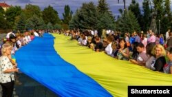 Учасники свята з нагоди Дня національного прапора тримають його на вулиці Ужгорода. Закарпаття. 23 серпня 2016 року