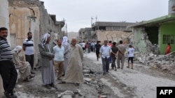 People inspect damage at the site of two car bomb blasts in the Iraqi town of Tuz Khormato on May 21.