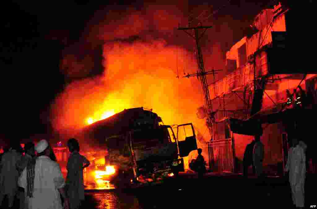 Men gather around a burning NATO oil tanker near a market in the Pakistani city of Peshawar on July 16. According to security officials, three people were killed and 16 others wounded when militants blew up a NATO oil tanker and opened fire on another in Pakistan's troubled northwest.Photo by A. Majeed for AFP