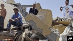 People stand in the rubble of a home in the Libyan city of Zliten that was reportedly destroyed by a NATO bomb in August 2011.