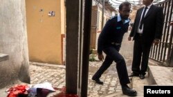 A policeman walks past a pool of blood while combing the area for attackers at the site of a bomb attack at the district court in Islamabad, March 3, 2014.