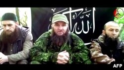 A screen grab taken from an undated video posted on July 3 that shows a man identified as Russia's top Islamist leader Doku Umarov (center) recording his appeal at an undisclosed location.