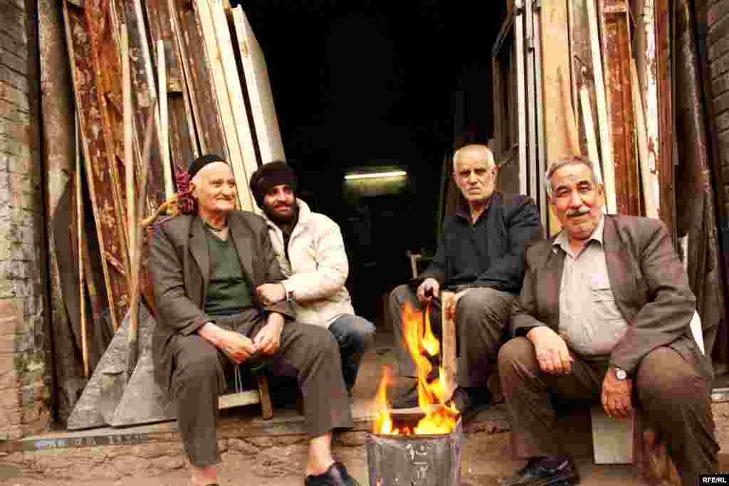 Men warm up on a cold day outside their carpentry workshop. Agha Mahmud, second from left, has worked here since age 10.